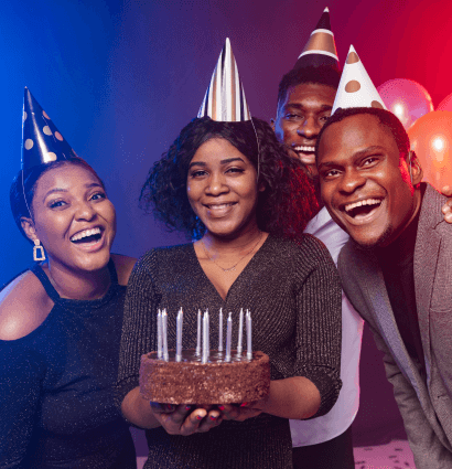 people with birthday cones on head and a cake in hand